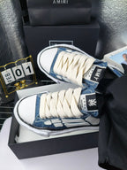 Blue denim low-top sneaker with white laces and white patterned side, close-up angle