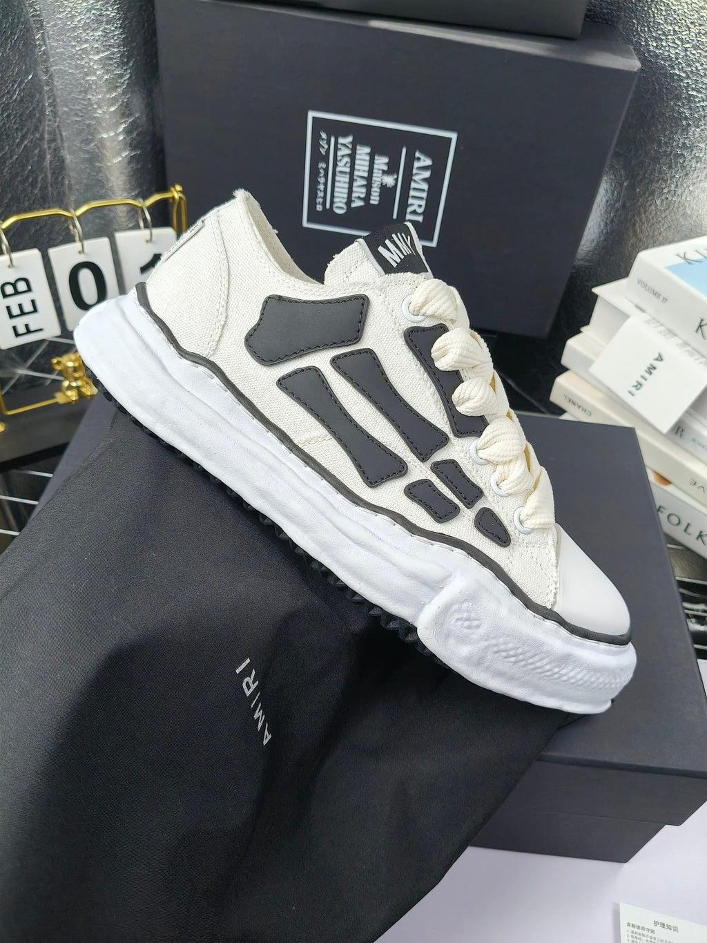 Low-top sneakers with white uppers, gray graphic panels, and white lace-up