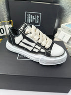 Low-top sneakers with black uppers, white side panels, and white lace-up