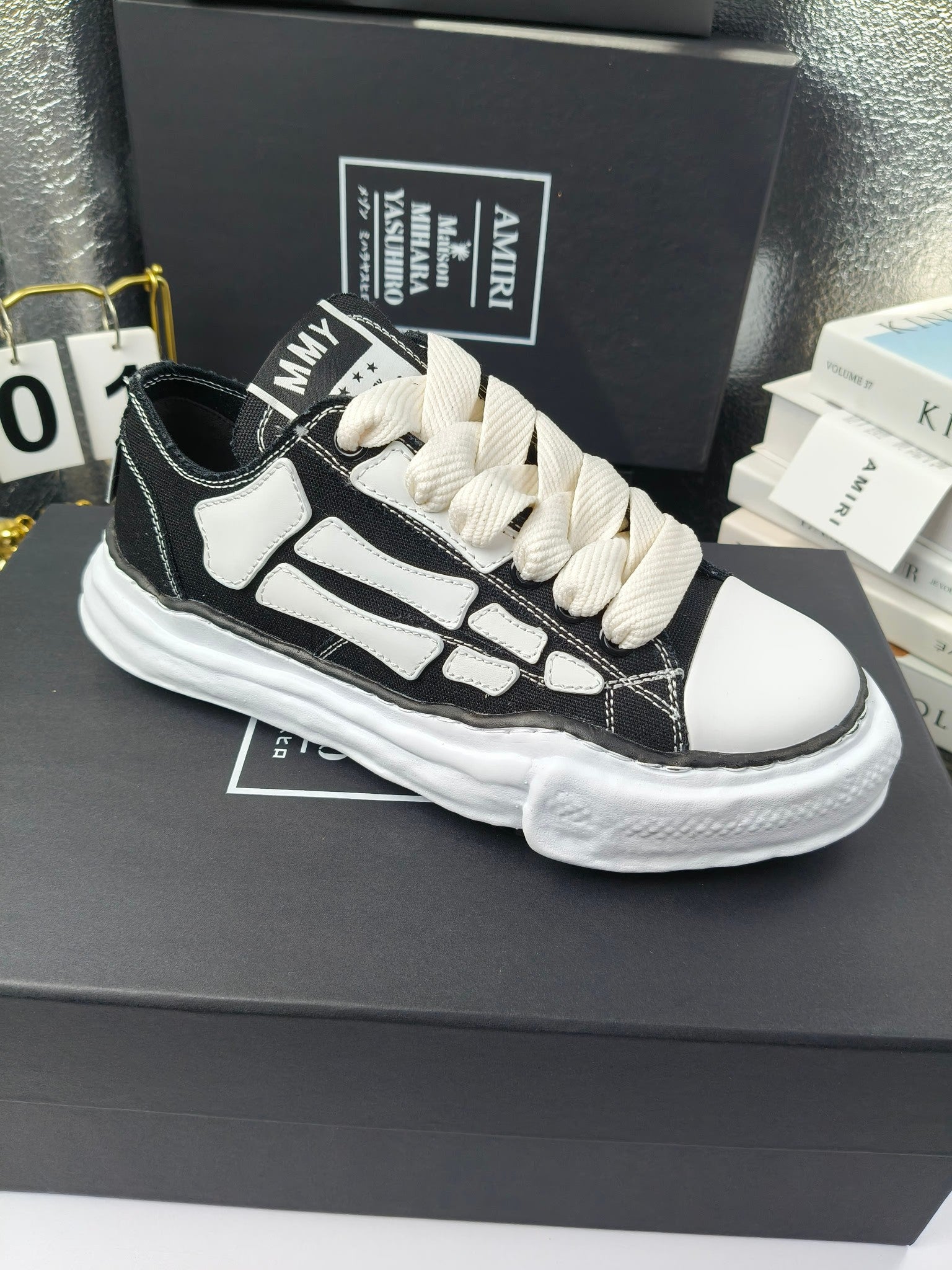 Low-top sneakers with black uppers, white side panels, and white lace-up