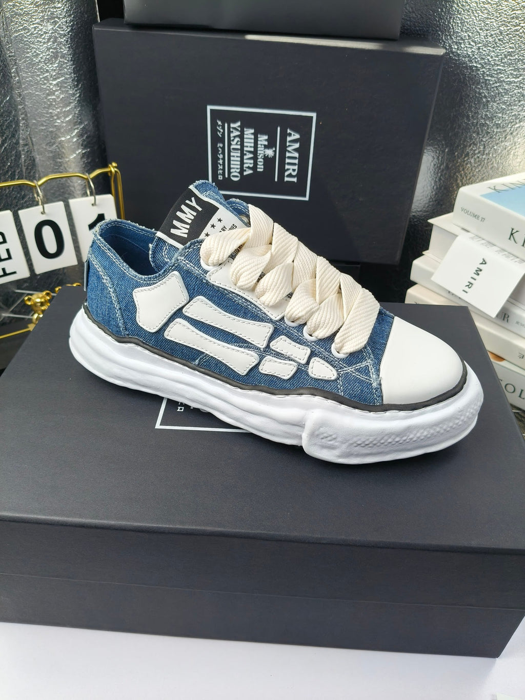 Pair of low-top sneakers with blue denim uppers, light blue graphics, and white laces