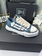 Pair of low-top sneakers with blue denim uppers, light blue graphics, and white laces