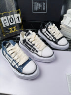 Three pairs of lace-up sneakers in white, blue, and black with contrasting panels
