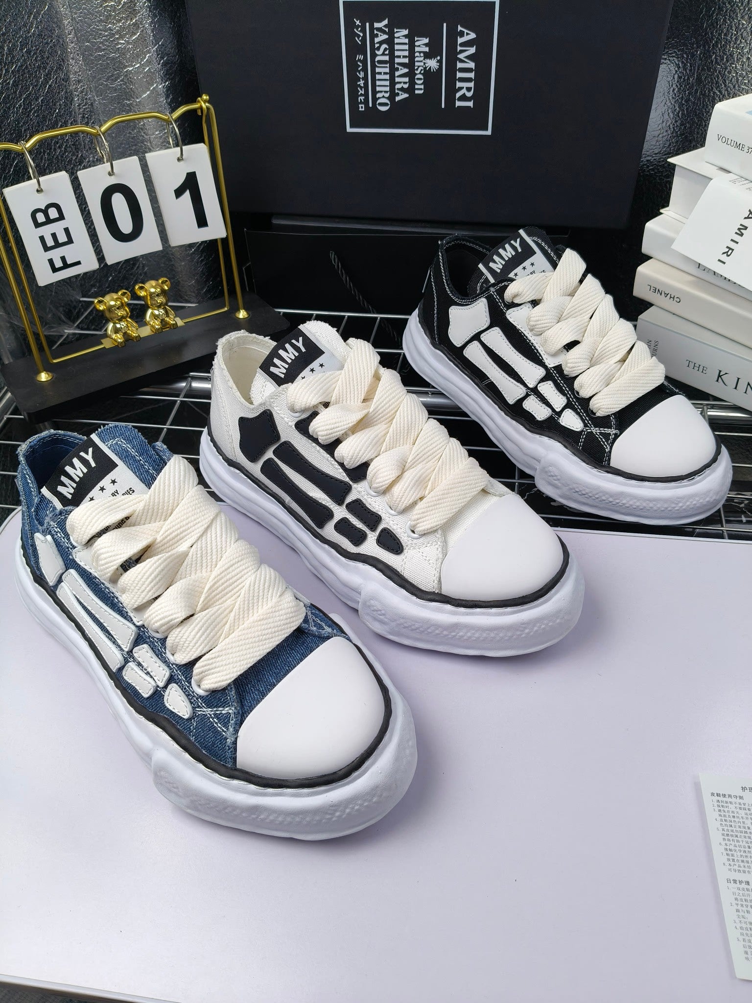 Three pairs of lace-up sneakers in white, blue, and black with contrasting panels