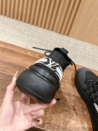 Black lace-up sneakers with bold white "LV" side band and thick rubber sole.