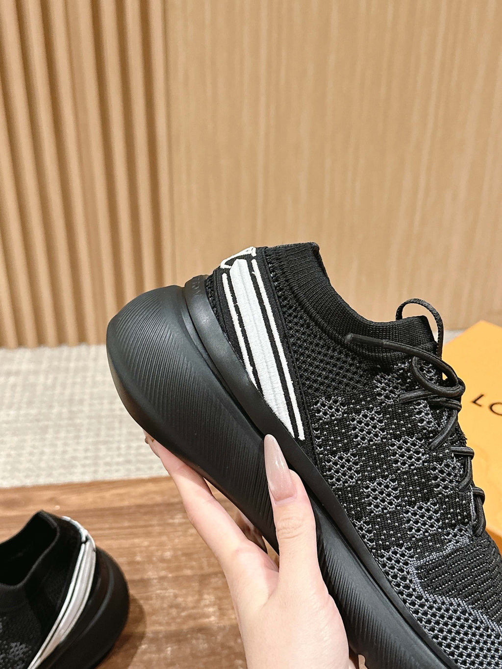 Black sneakers with white side stripe, lace-up design, and thick rubber sole.