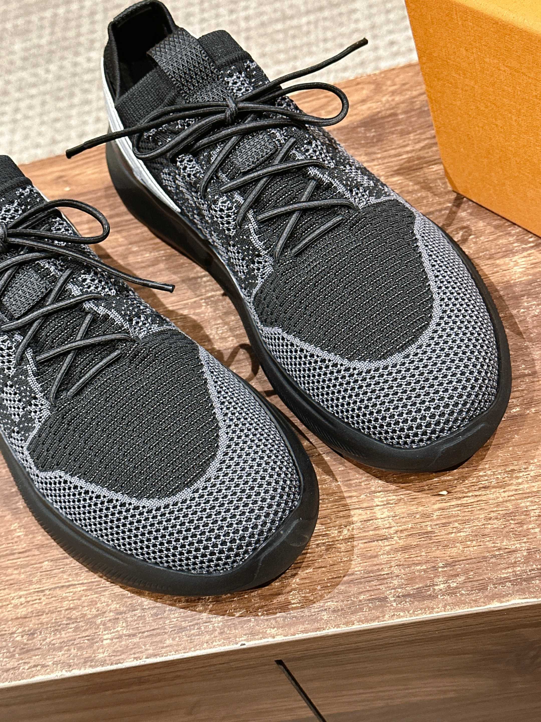 Black knit lace-up sneakers, close-up of textured upper and laces with thick sole.