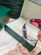 Rolex watch with blue face and silver bracelet, side view in a display box
