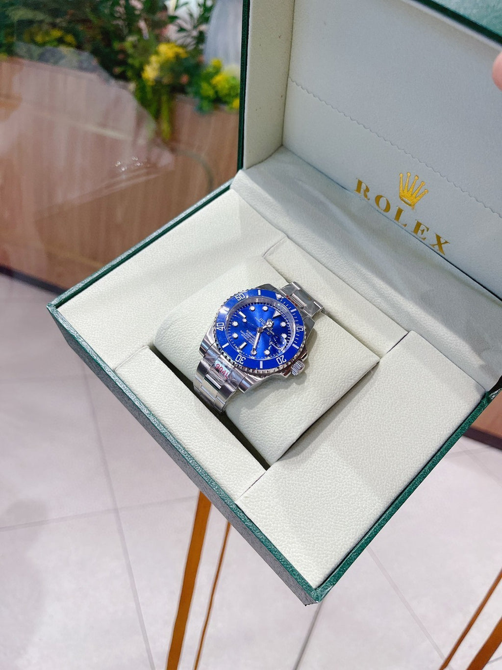 Rolex watch with blue dial and silver bracelet in a green-trimmed gift box