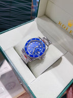 Rolex watch with blue dial and silver metal bracelet on a white cushion