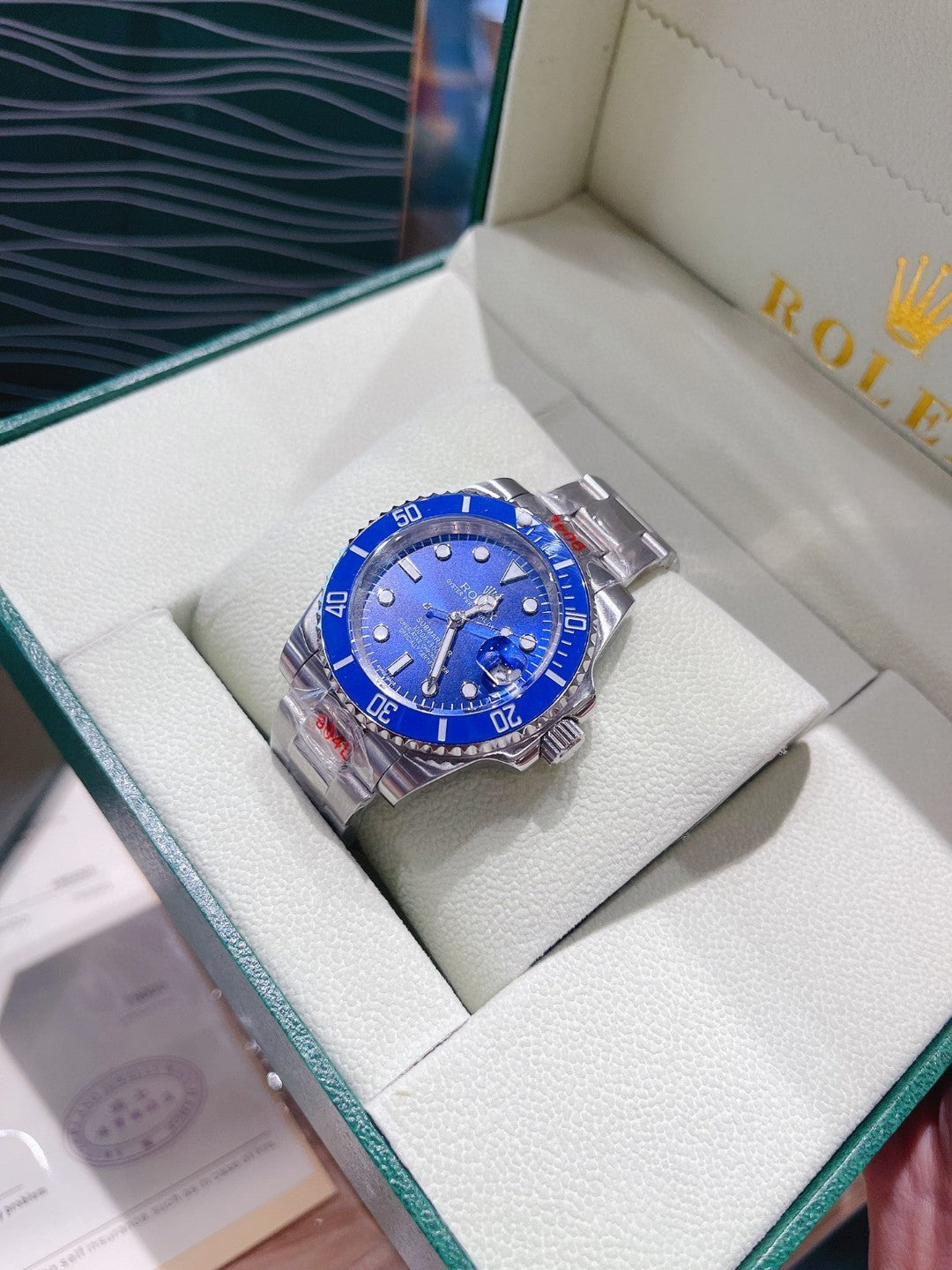 Rolex watch with blue dial and silver metal bracelet on a white cushion