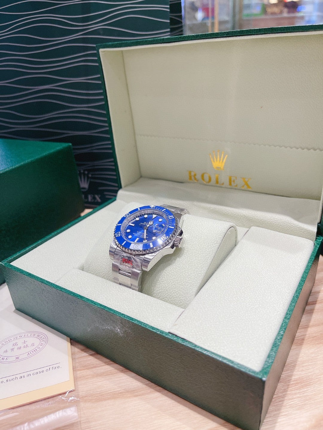 Rolex watch with blue dial and silver bracelet in a green-trimmed display box