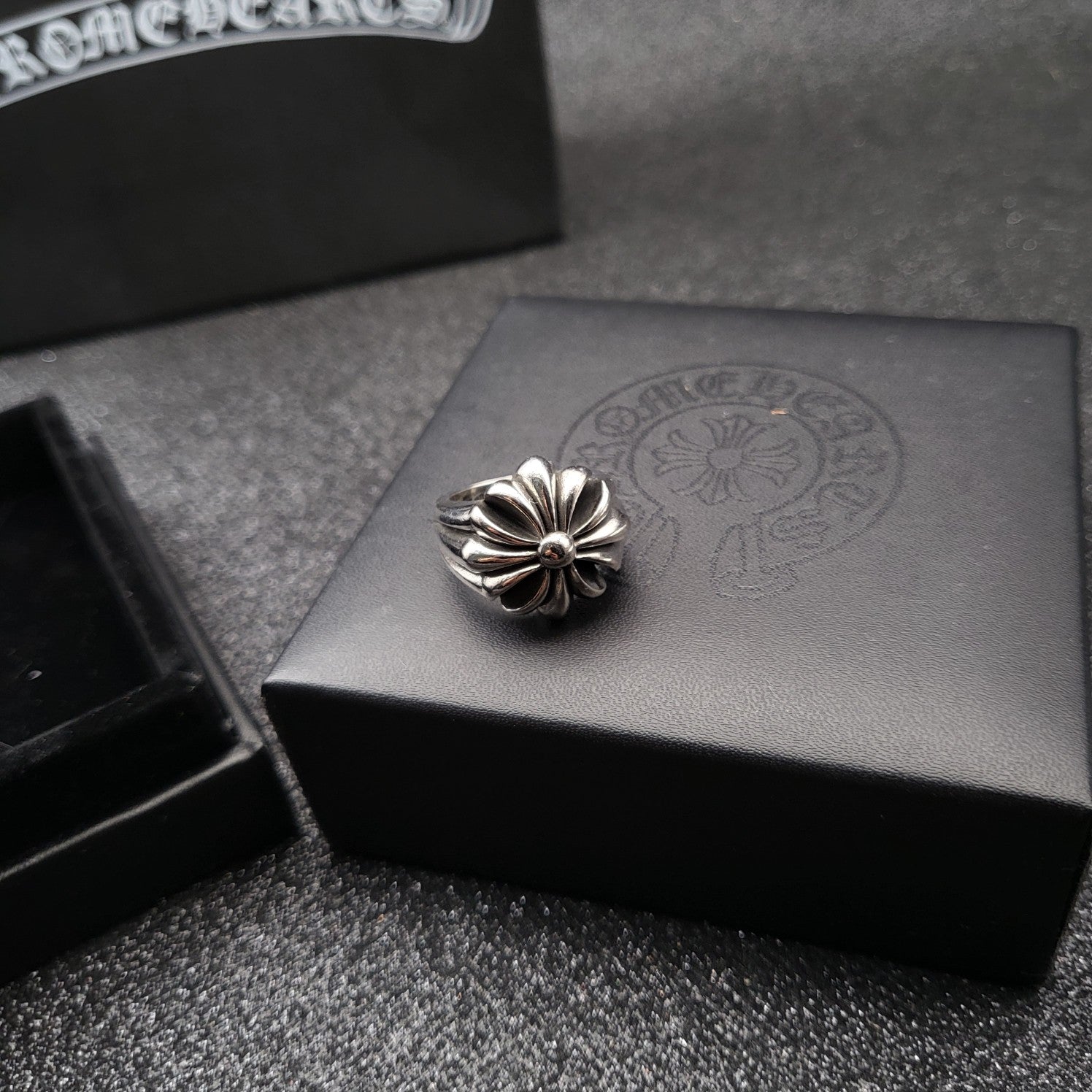 Silver-tone flower ring on gray jewelry box