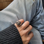 Silver-tone flower ring worn on hand with dark knit sleeve