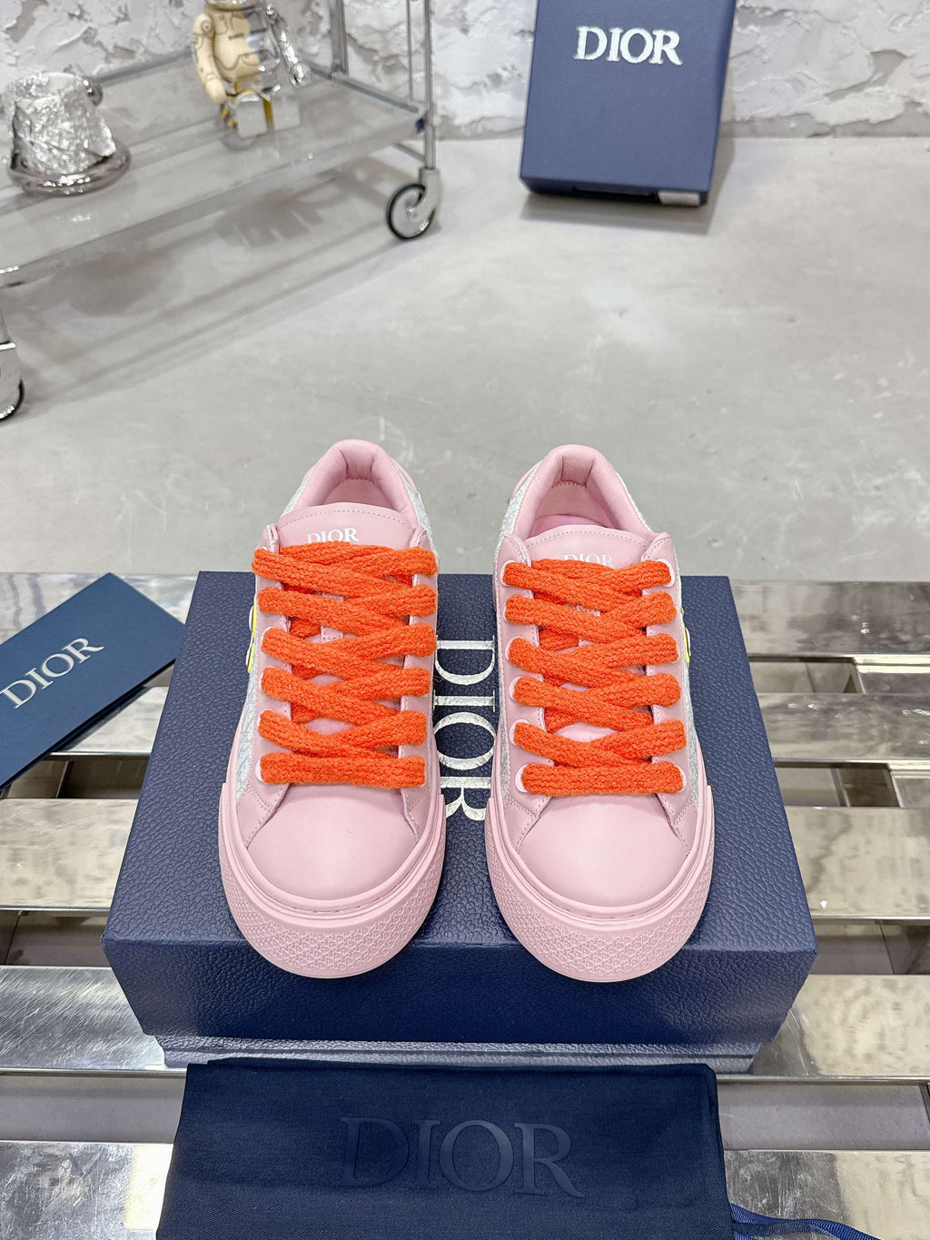 Pair of pink and white low-top sneakers with orange laces