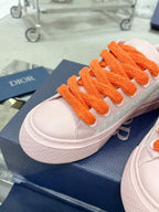 Pink and white low-top sneaker toe with orange laces