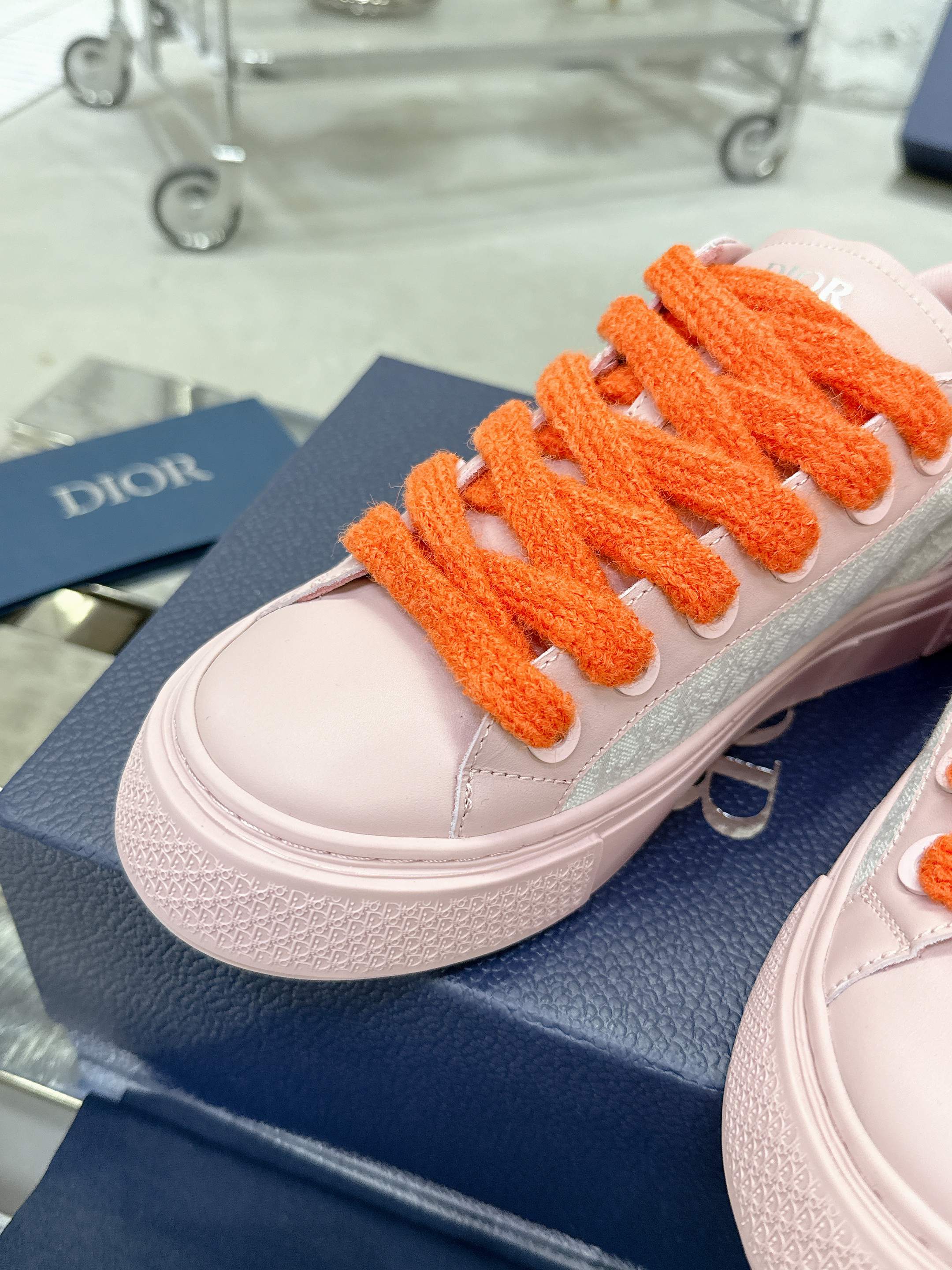 Pink and white low-top sneaker toe with orange laces