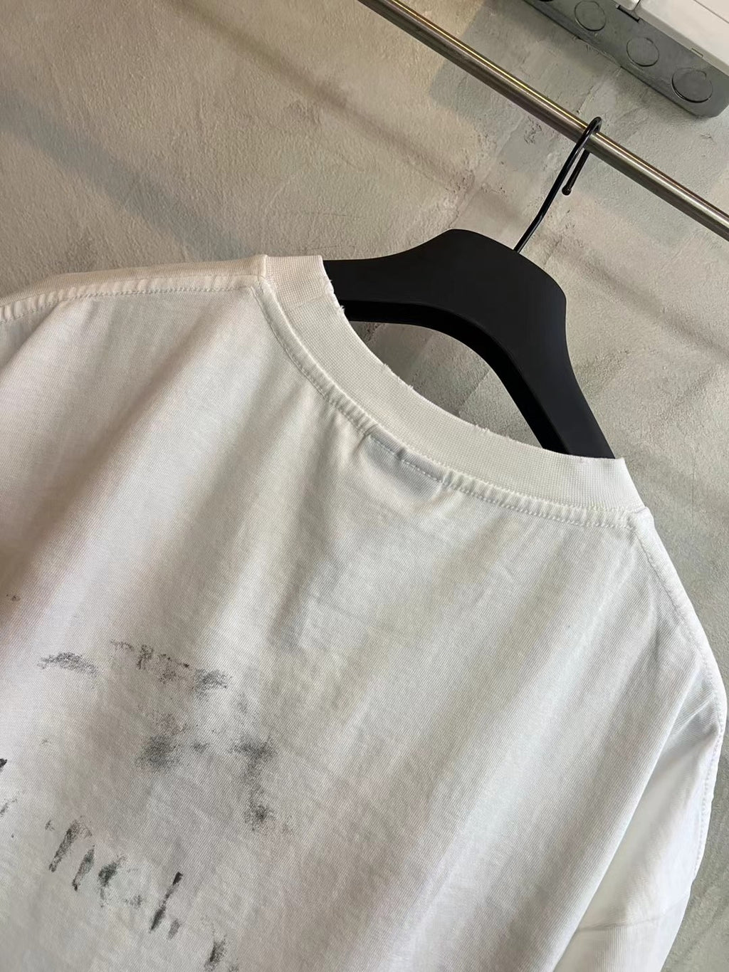 White crew-neck T-shirt showing distressed print on upper back