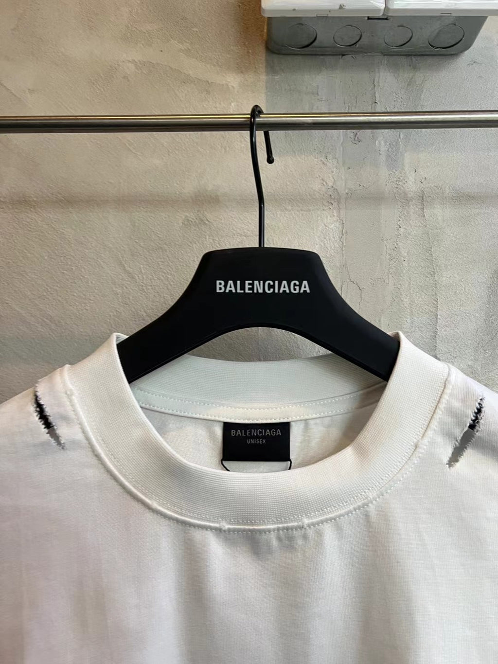 White crew-neck T-shirt on hanger with red marks near shoulders and neckline.