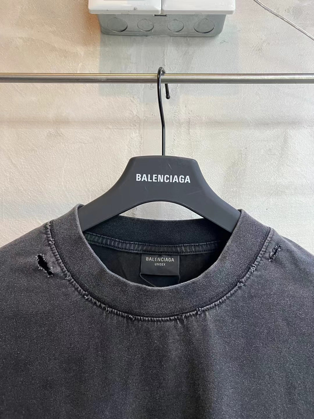 Balenciaga dark gray T-shirt with crew neck and distressed seams, hanging on BALENCIAGA tag
