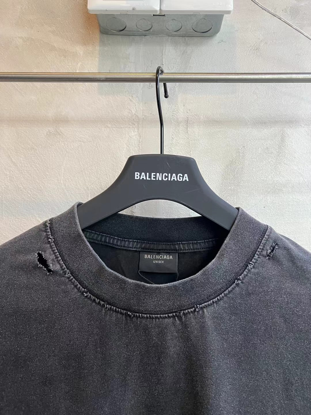 Balenciaga dark gray T-shirt with crew neck and distressed seams, hanging on BALENCIAGA tag