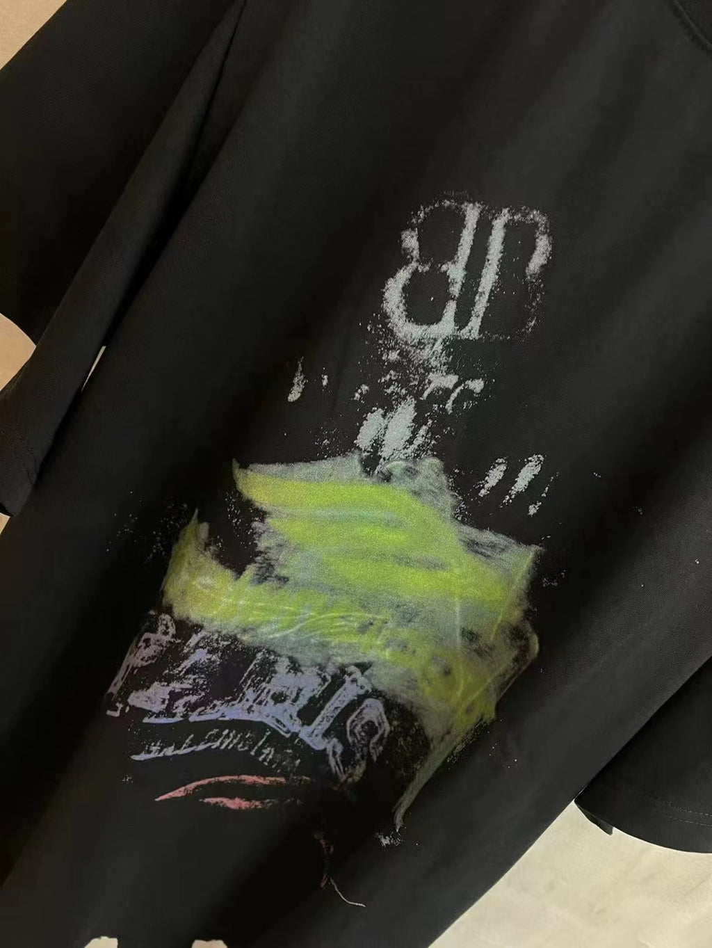 Black T-shirt close-up showing top part of graphic artwork with white and neon green ink