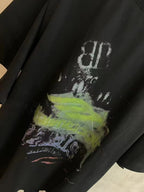 Black T-shirt close-up showing top part of graphic artwork with white and neon green ink