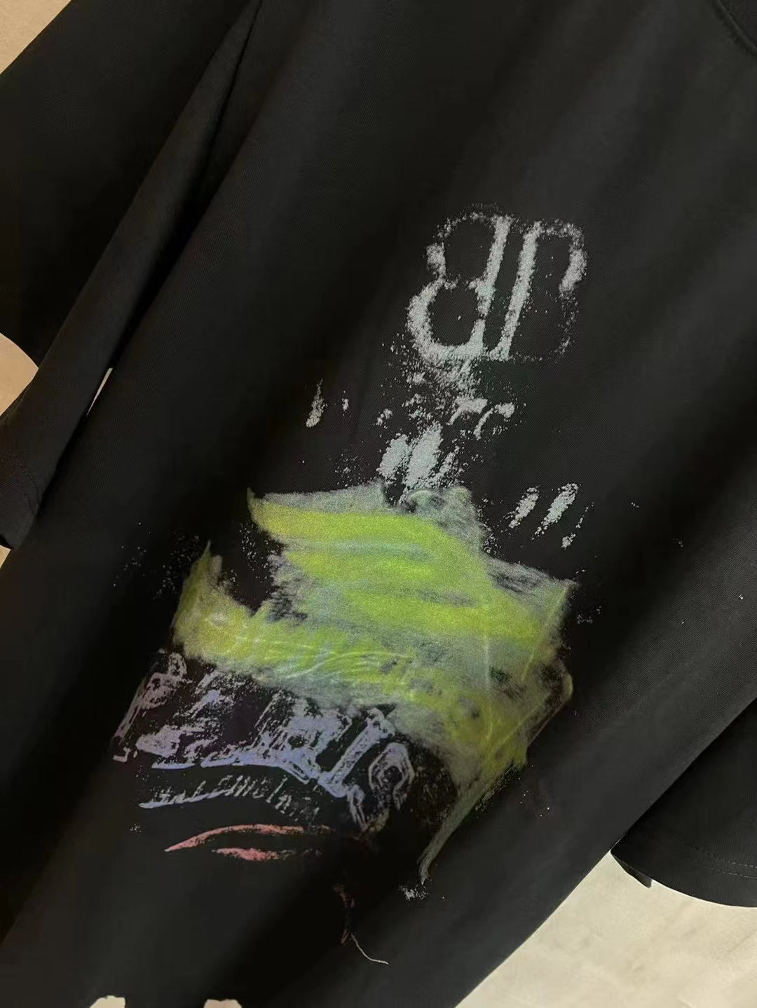 Black T-shirt close-up showing top part of graphic artwork with white and neon green ink