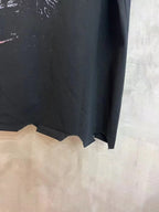 Black T-shirt bottom hem close-up with raw, uneven edges and partial neon print
