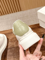 White sneaker with olive-green tongue and padded heel, held in hand