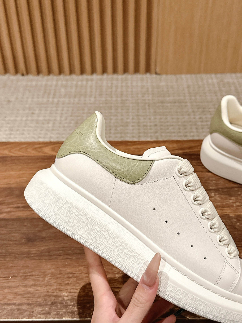 White sneakers with olive-green side panel and lace-up front, three-quarter view