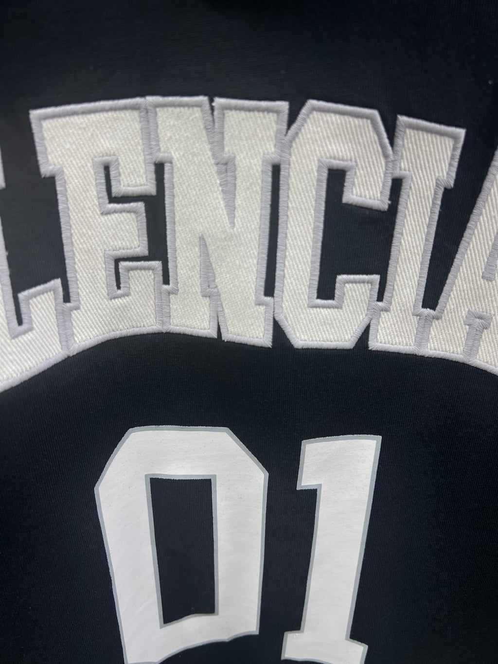 Balenciaga T-shirt fabric close-up with textured “BALENCIAGA” and “01” print details
