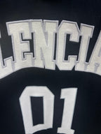 Balenciaga T-shirt fabric close-up with textured “BALENCIAGA” and “01” print details