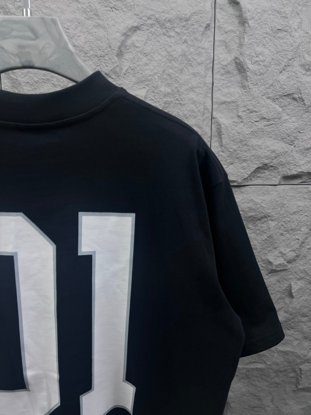 Balenciaga T-shirt back close-up with white “01” number print on dark navy fabric
