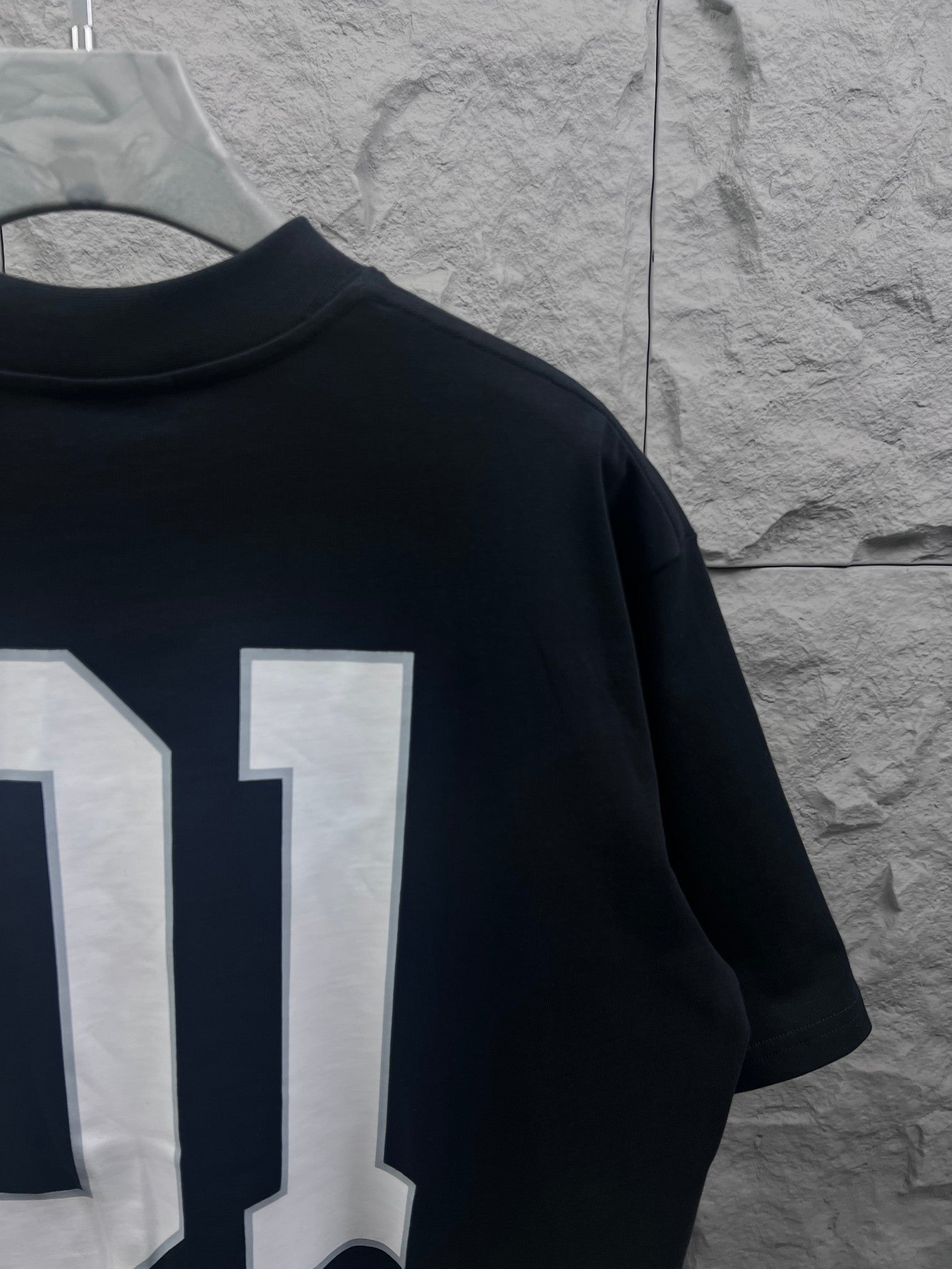 Balenciaga T-shirt back close-up with white “01” number print on dark navy fabric