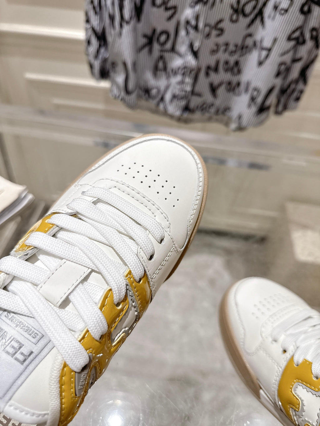 Fendi white leather sneakers with yellow logo stripe, lace-up front view