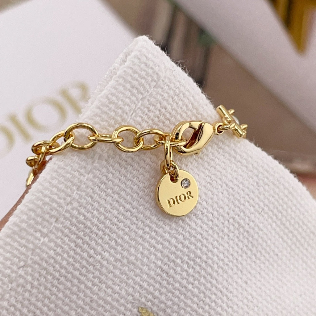 Gold chain bracelet with pearl beads and DIOR logo charm on a clasp