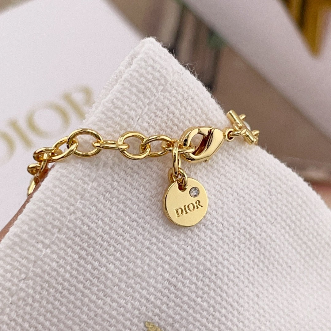 Gold chain bracelet with pearl beads and DIOR logo charm on a clasp