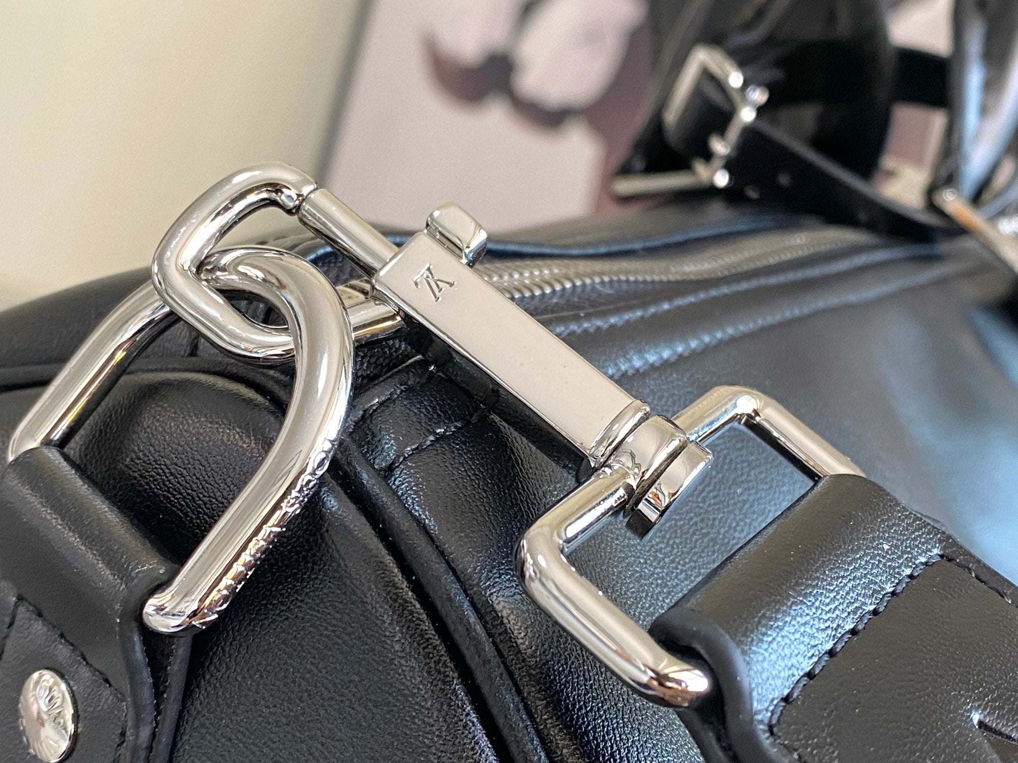 Louis Vuitton men's duffel bag close-up of metal hardware and strap loops on dark leather