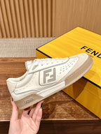 Cream white unisex sneaker held in hand, with Fendi logo on heel