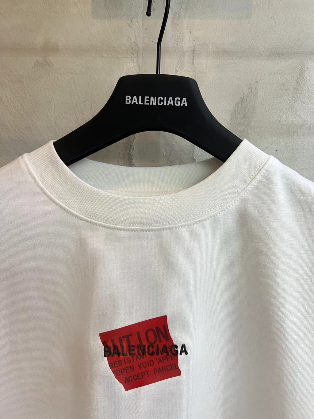 Balenciaga white T-shirt close-up of red logo patch and crew neckline