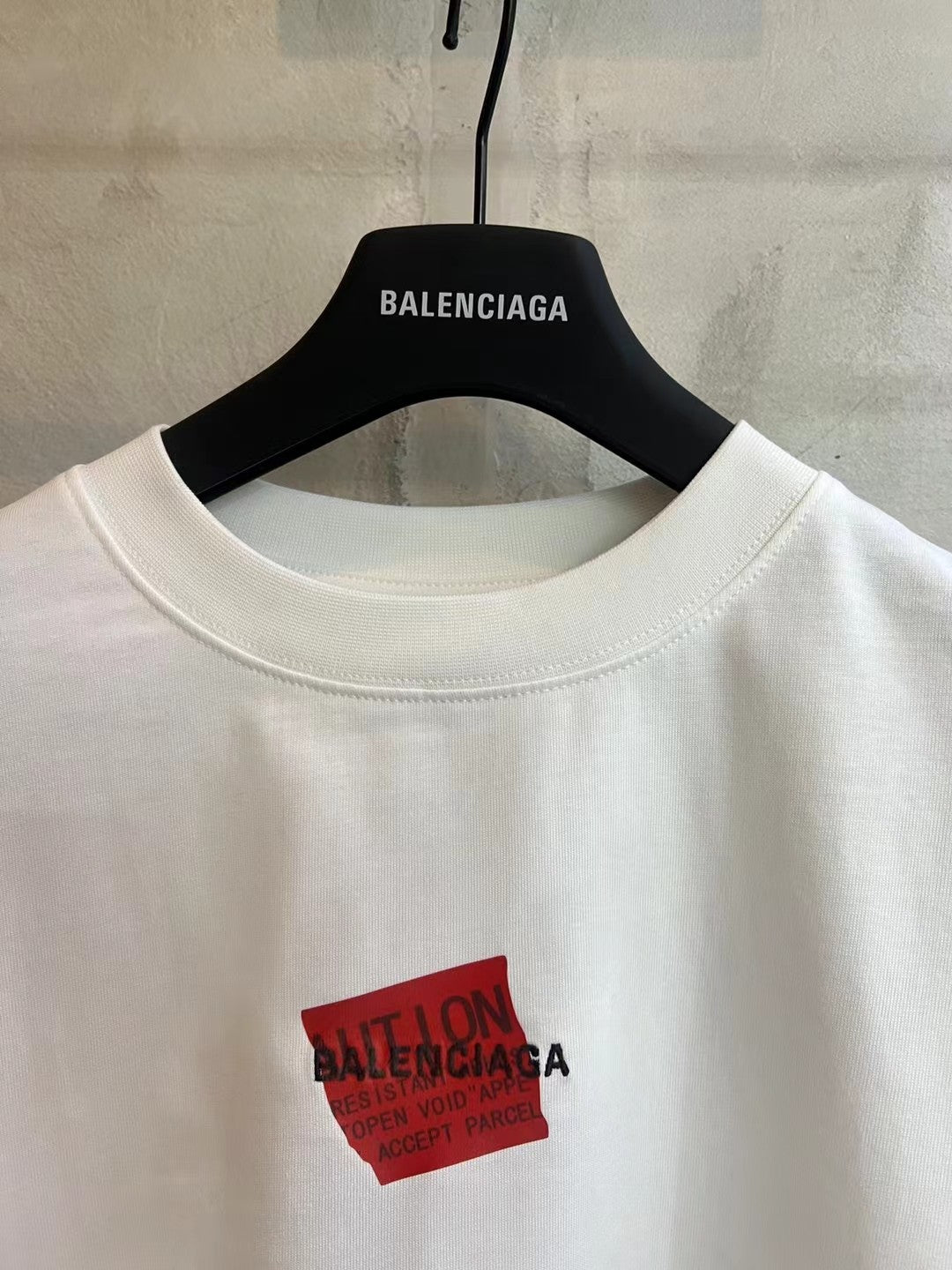 Balenciaga white T-shirt close-up of red logo patch and crew neckline