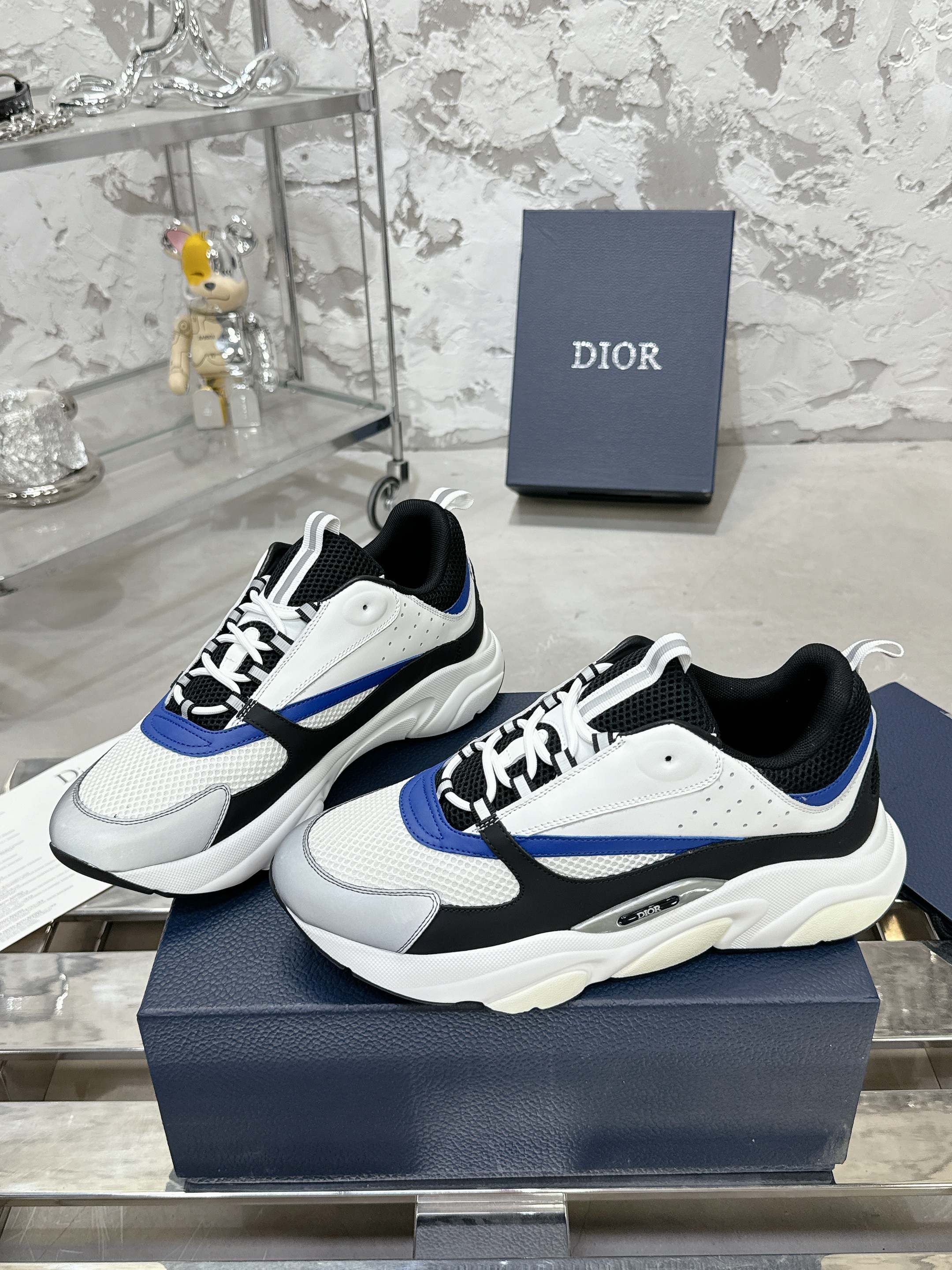 Pair of low-top sneakers with white mesh upper, black overlays, blue stripe and laces