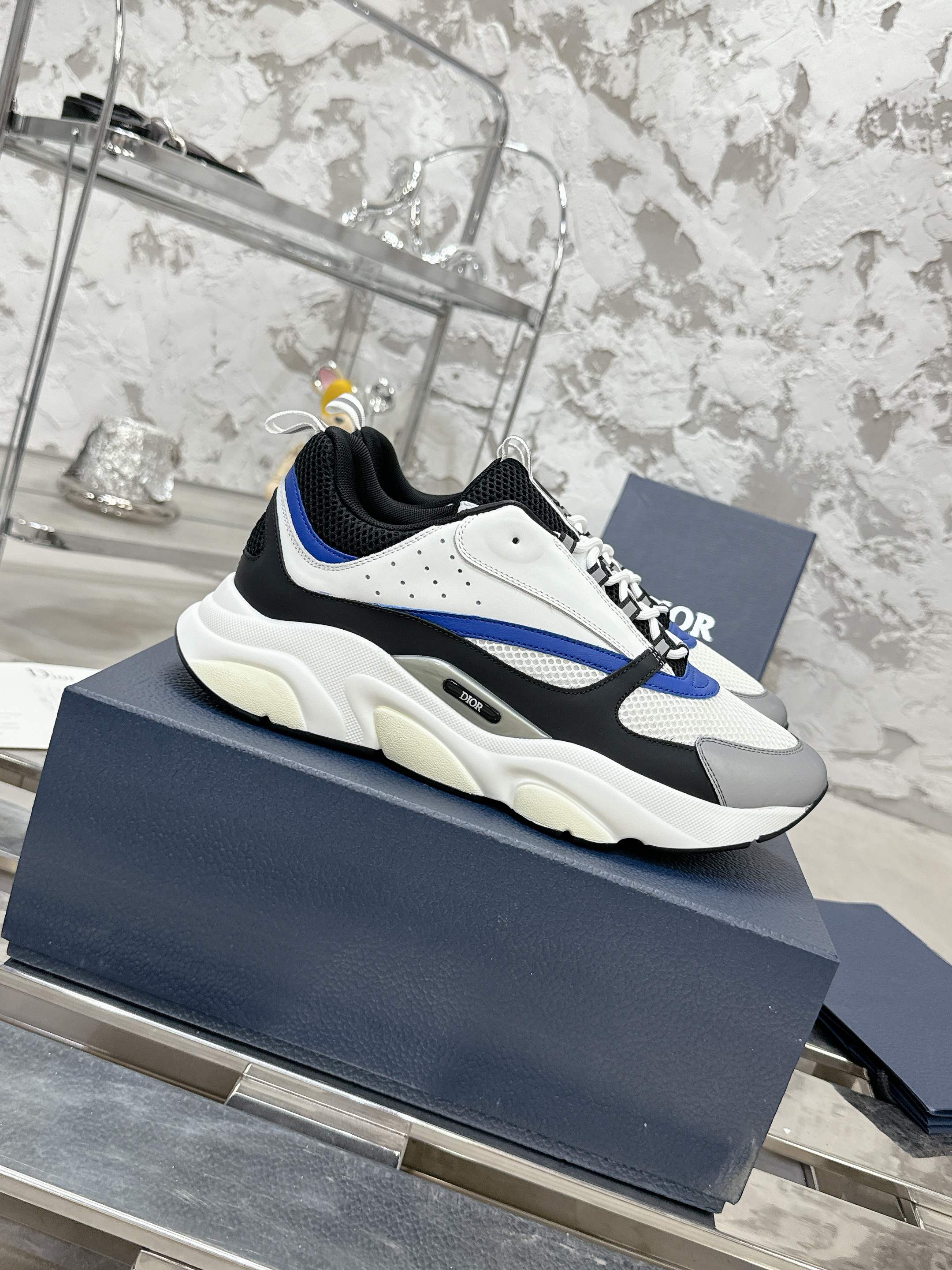 Low-top sneakers angled view, white upper with black paneling and blue stripe detail