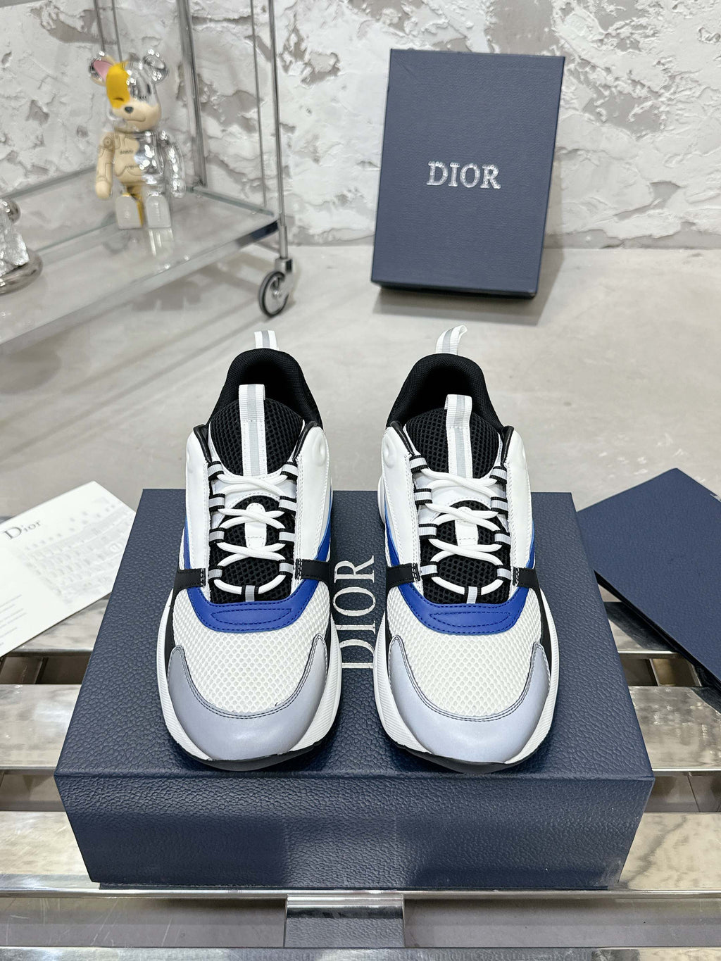 Low-top sneakers in white with black and blue accents, lace-up with textured sole