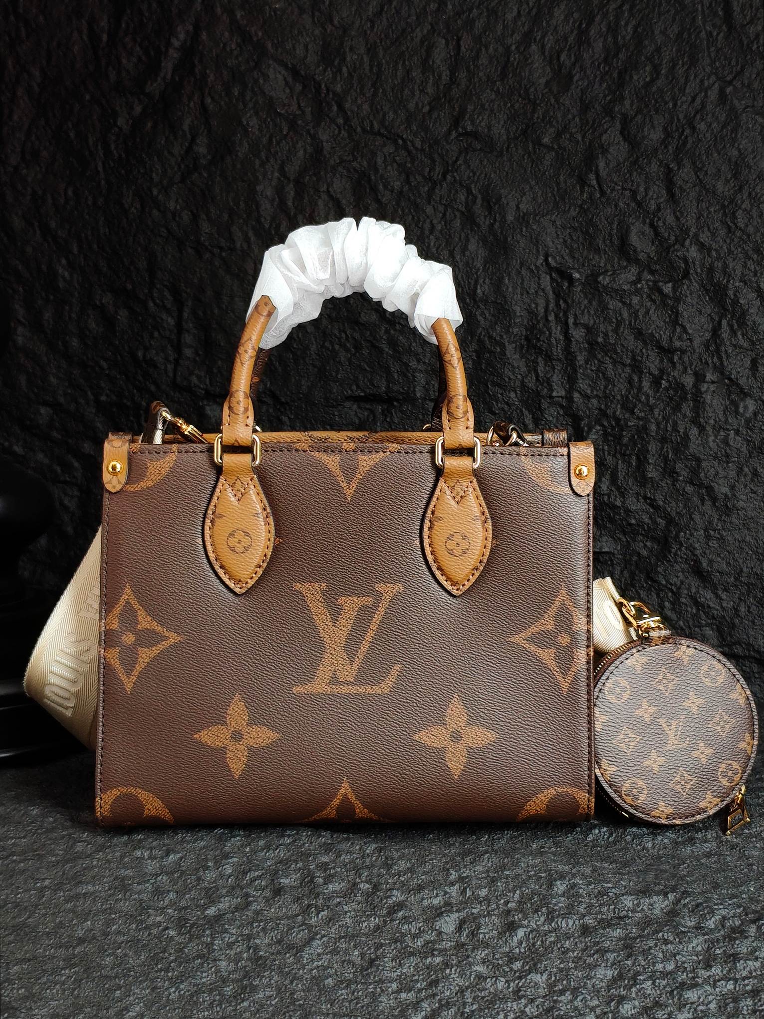 Brown monogram handbag with ribbon handles, front pockets, and round crossbody pouch