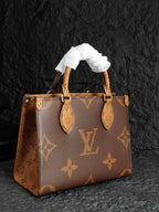 Brown monogram tote bag with ribbon top handles and gold-tone hardware
