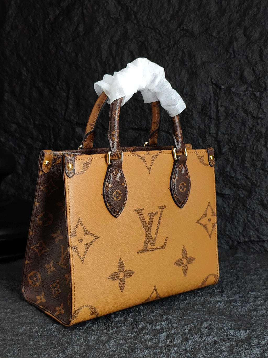 Light tan monogram handbag with ribbon top handles and structured square sides