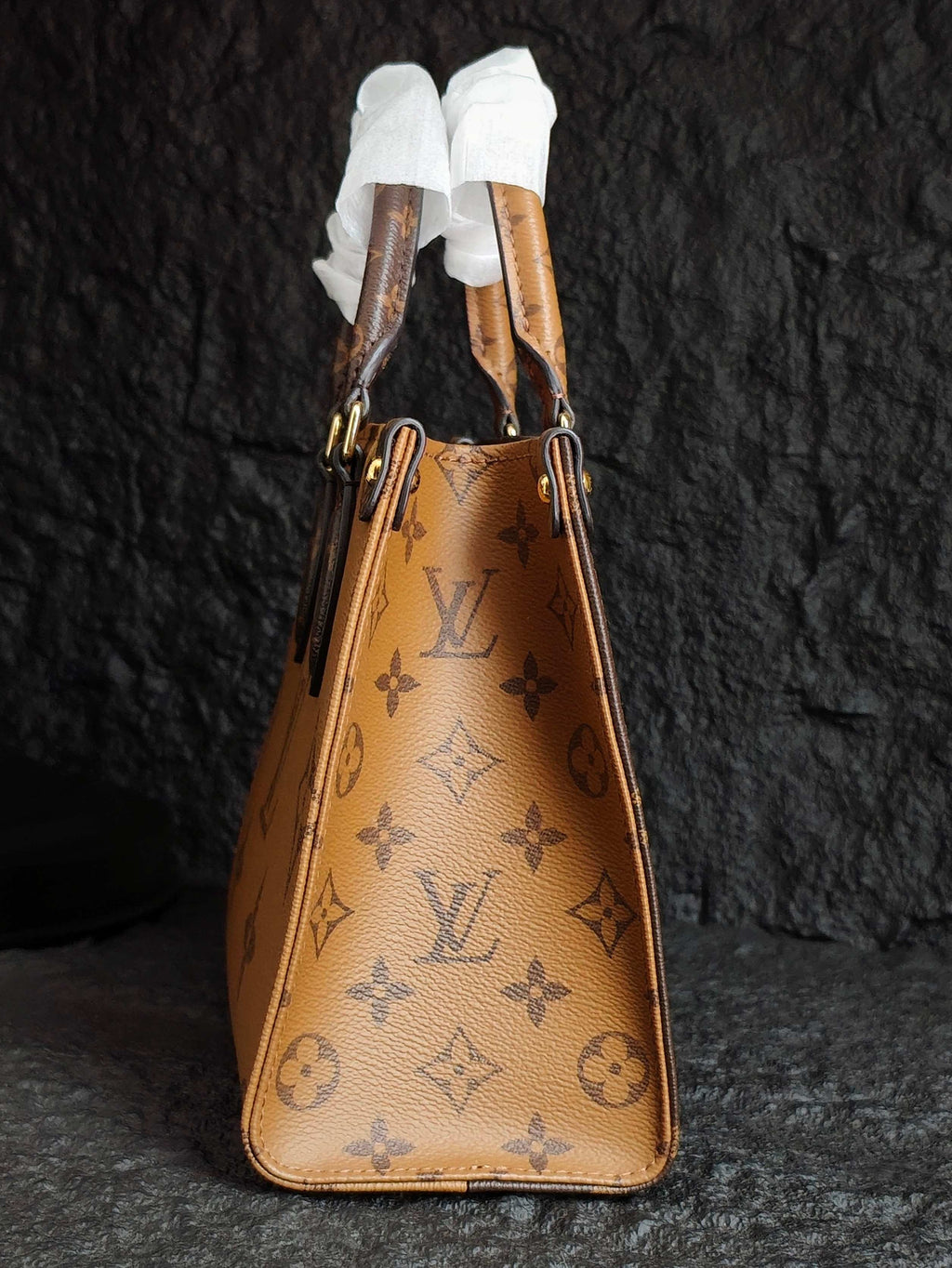 Tan monogram drawstring-style handbag with ribbon handles and gold-tone grommets