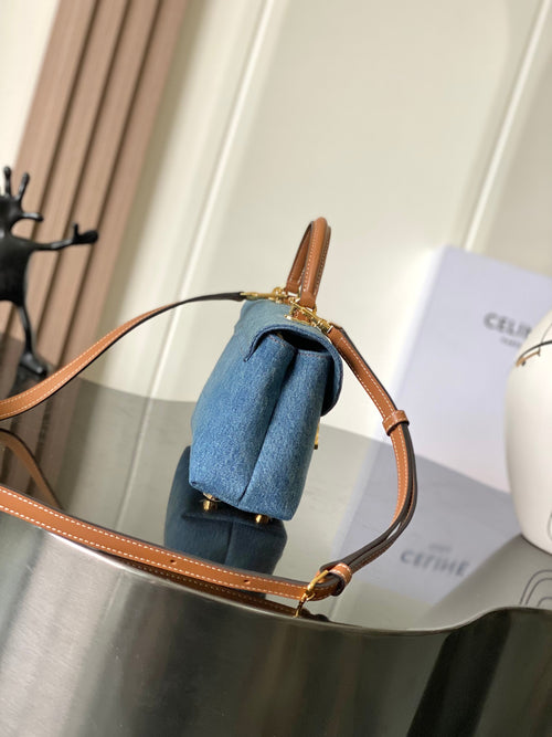 Denim top-handle bag with tan leather strap and gold-tone hardware, blue wash